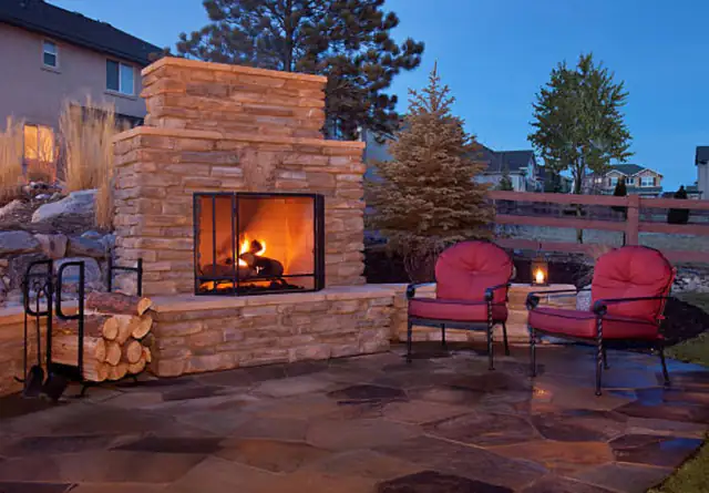 Outdoor stone fireplace on a patio, Newcastle upon Tyne Stone outdoor fireplace on a garden patio with two red armchairs