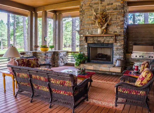 Stone fireplace in a garden room, Newcastle Stone fireplace in a bright garden room with wicker sofas and cushions